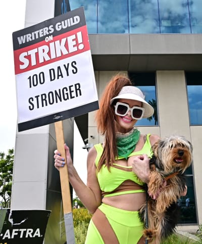Actress Phoebe Price holds her dog and a picket sign joining members of the Writers Guild of America and the Screen Actors Guild