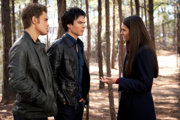 Stefan, Damon, and Elena standing in a forest in "The Vampire Diaries"